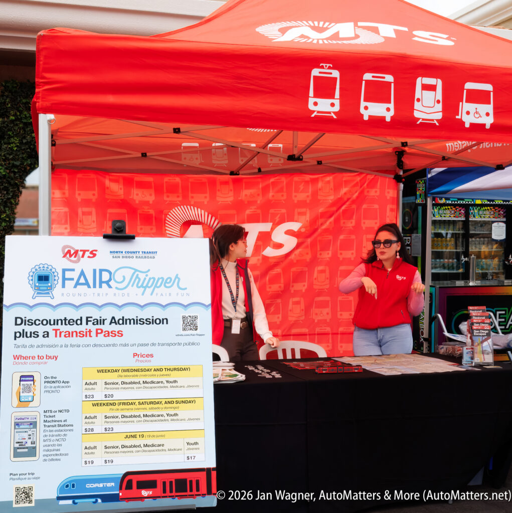 Two women stand at an MTS booth with a red canopy, providing information and selling discounted fair admission and transit passes for the FairTripper program.
