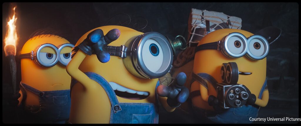 Three Minions in overalls explore a dark area; one holds a torch, another looks through a monocle, and the third carries a gadget.
