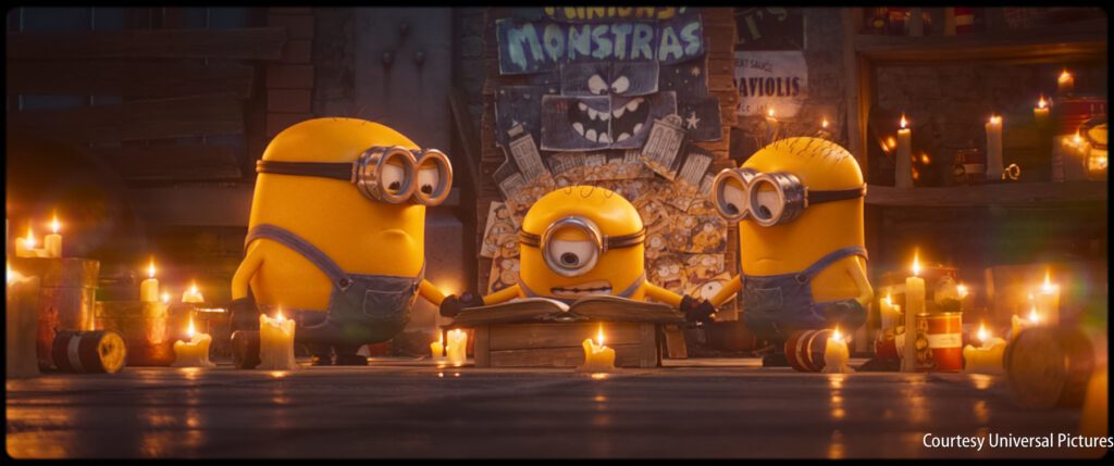 Three Minions are gathered around a book surrounded by lit candles in a dimly lit room with posters and debris on the walls.