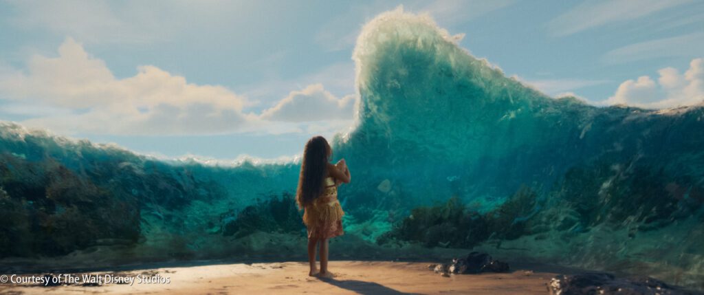 A girl with long hair stands on a sandy shore facing a large wave as the ocean parts, revealing the sea floor and underwater plants.