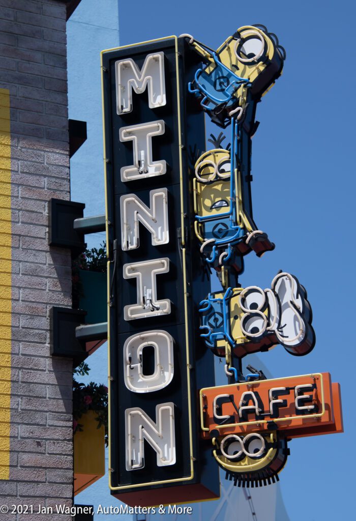 Neon sign reading "Minion Cafe" with Minion characters from the Despicable Me franchise on a building exterior.