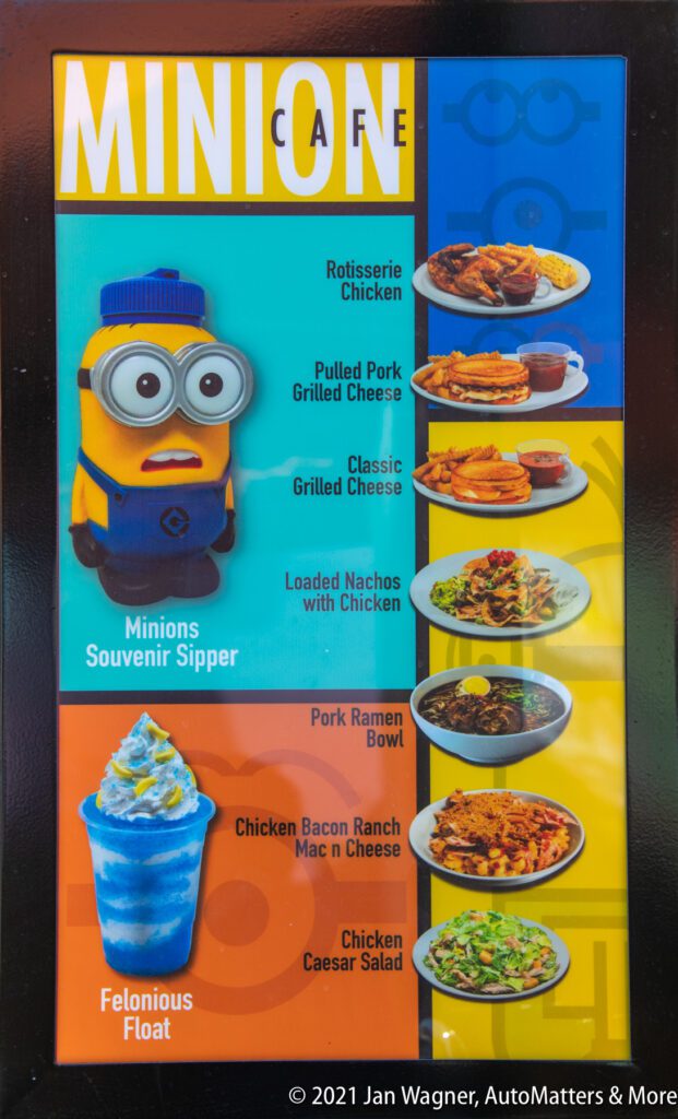 Colorful menu featuring a Minion souvenir sipper, rotisserie chicken, pulled pork and classic grilled cheese, nachos, pork ramen bowl, chicken mac & cheese, caesar salad, and a blue float.
