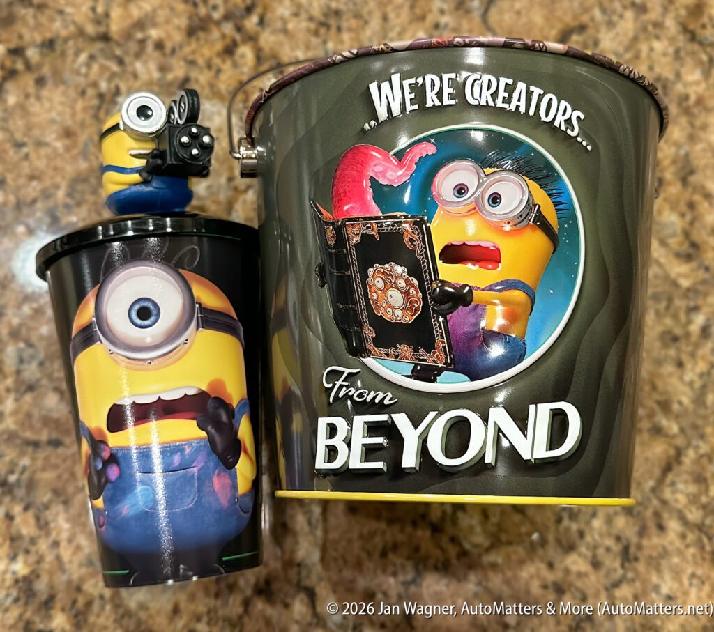 A Minions-themed popcorn bucket and cup, featuring Minion characters and the text "WE'RE CREATORS From BEYOND," on a speckled surface.