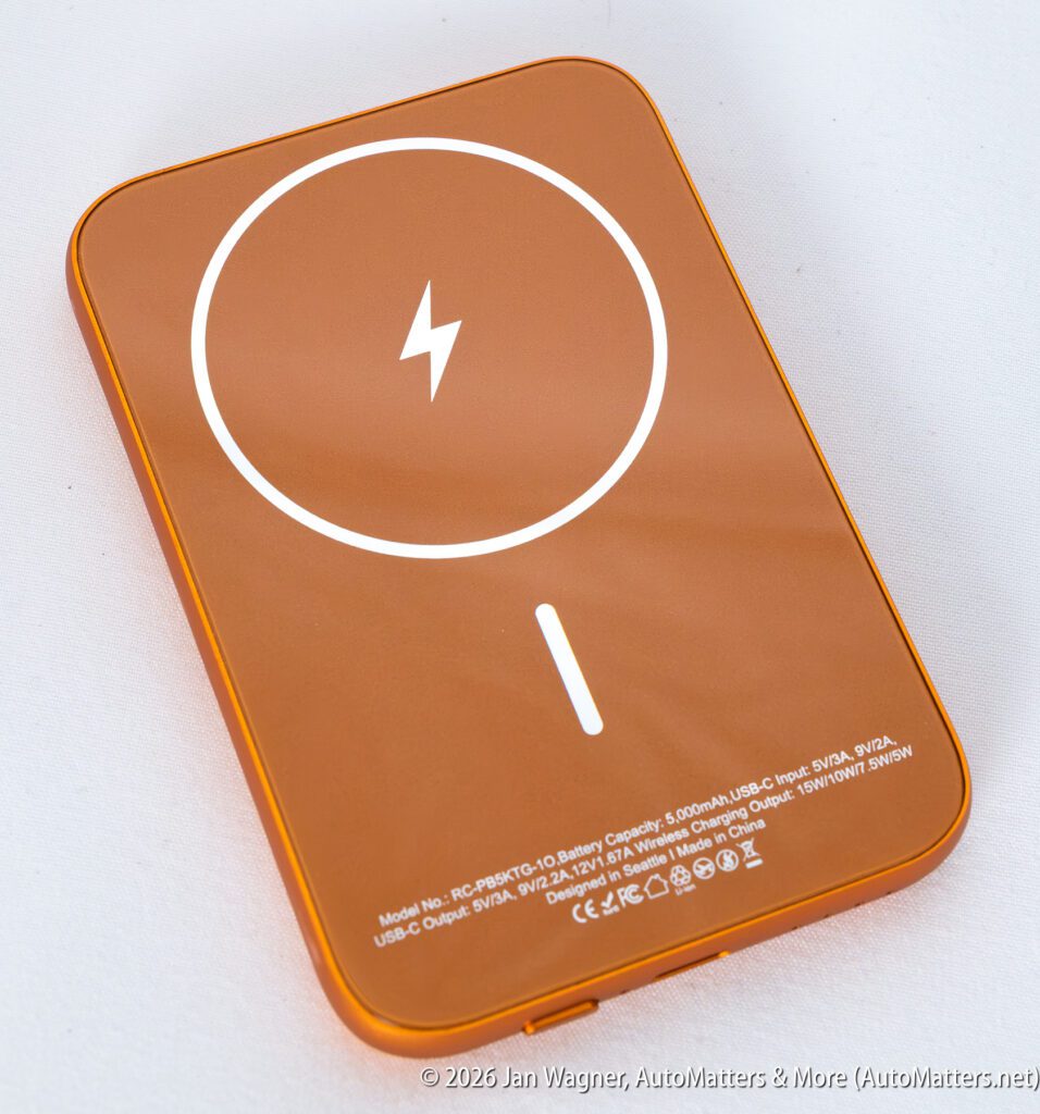 Orange wireless charging pad with a white lightning icon and technical specifications printed on its surface, placed on a white background.