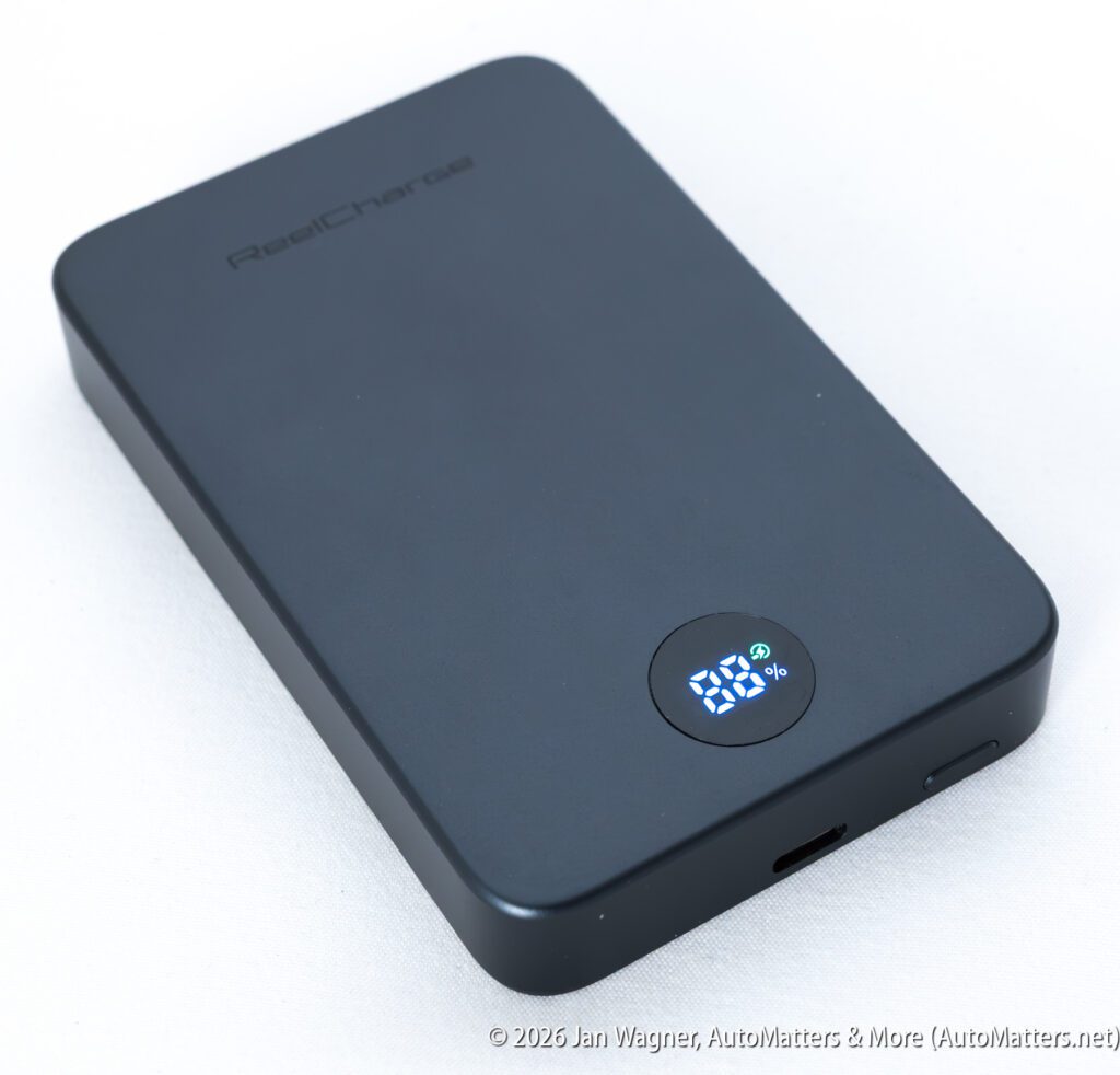 A black portable power bank with a digital display showing 99% charge, placed on a white surface.