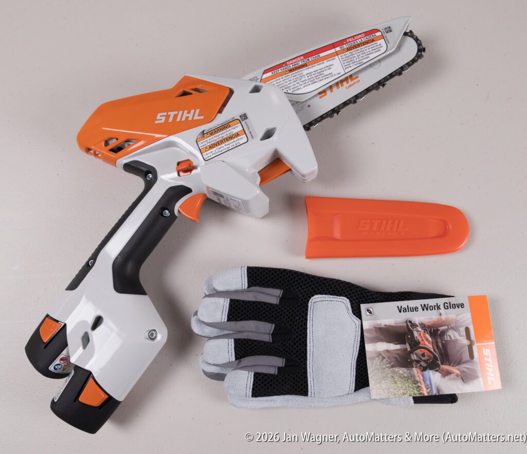 A small STIHL battery-powered chainsaw, orange blade cover, and a package of Value Work Glove are displayed on a light surface.