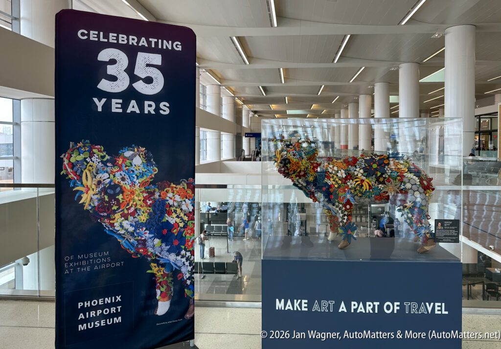 A colorful animal sculpture and a sign celebrating 35 years of museum exhibitions at the Phoenix Airport Museum are displayed in an airport terminal.
