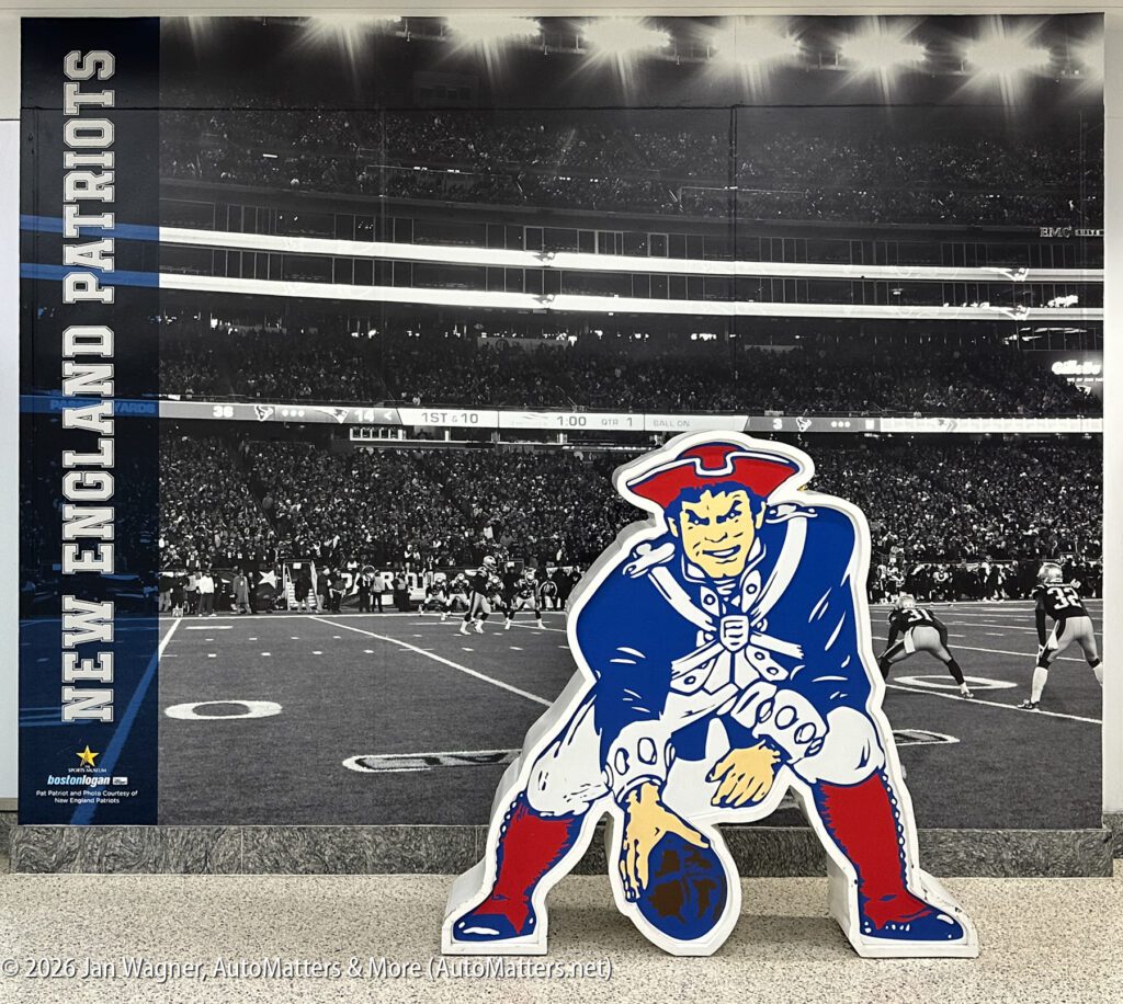 Cutout of New England Patriots mascot in front of a mural showing a football game and “NEW ENGLAND PATRIOTS” text on the left side.