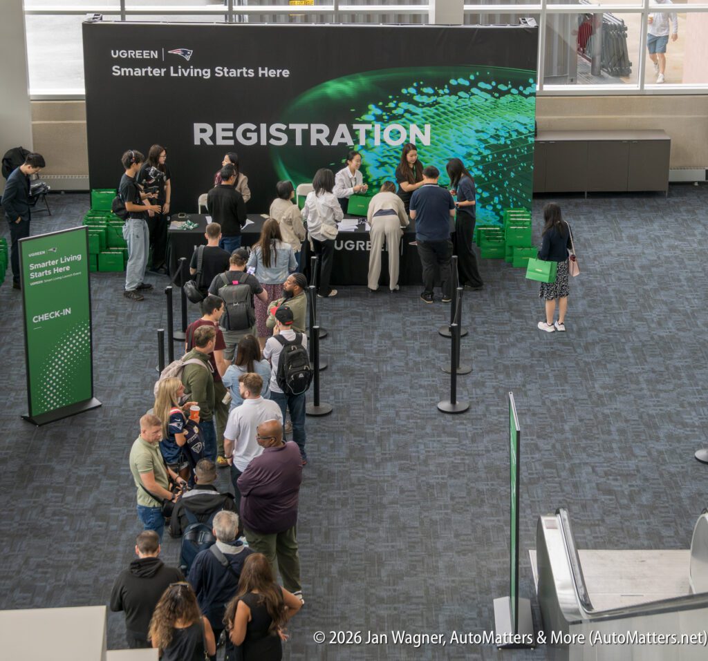 People stand in line at a registration desk with a large “UGREEN Smarter Living Starts Here” banner in the background at an indoor event.