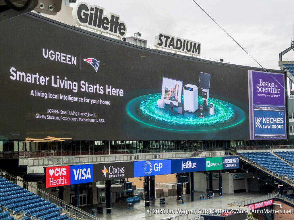 Large digital billboard at Gillette Stadium displays UGREEN smart home ad, Boston Scientific logo, and Keches Law Group info above stadium seats and sponsor signs.