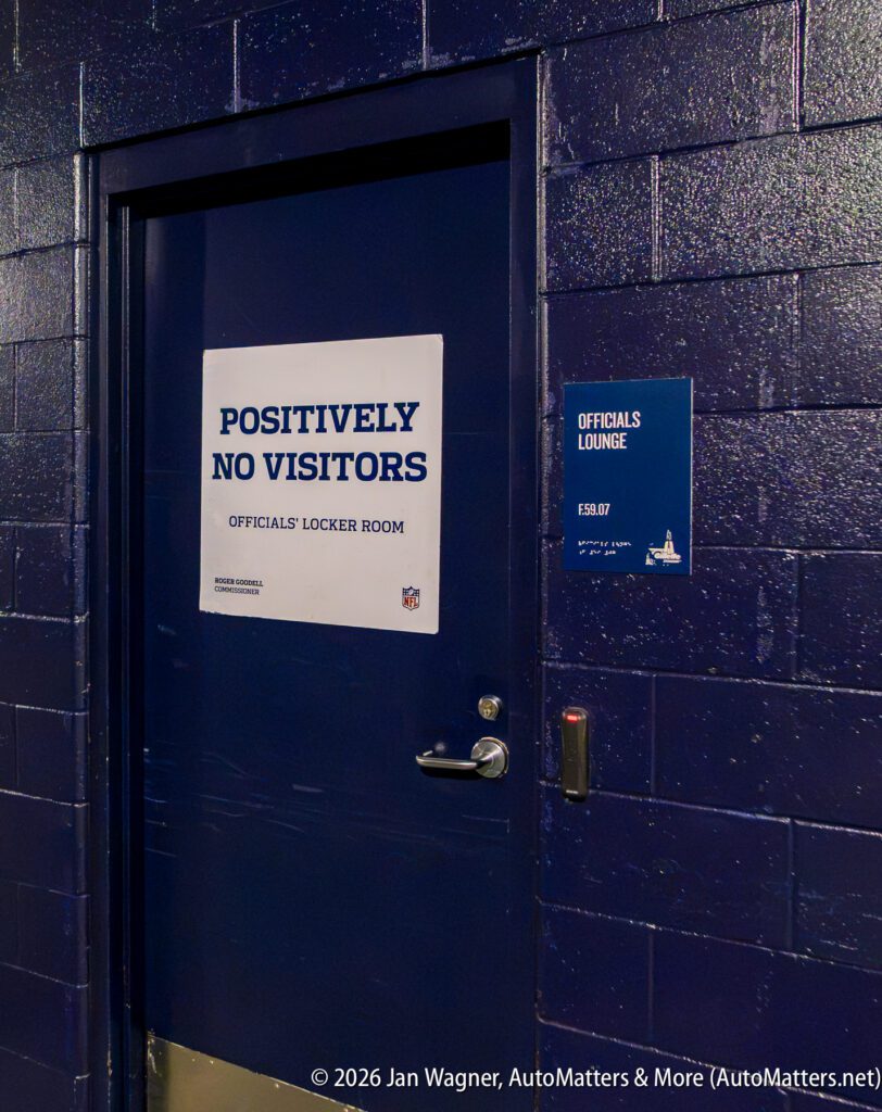A dark blue door labeled “Positively No Visitors, Officials’ Locker Room” with a smaller sign reading “Officials Lounge” on the wall beside it.