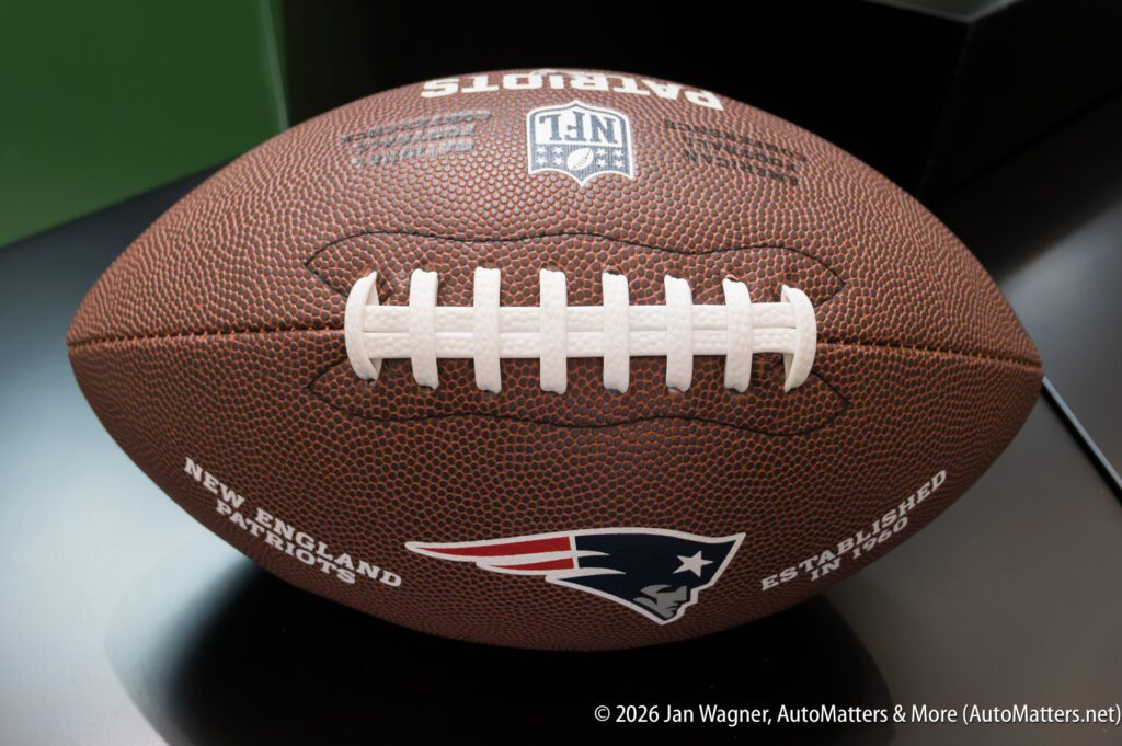 A New England Patriots football with the team logo and NFL branding rests on a dark surface.