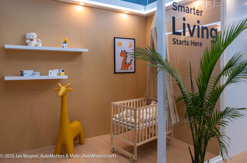 A modern nursery with a crib, yellow giraffe chair, stuffed bear, and playful wall decor. Text on the wall says “Smarter Living Starts Here.”.