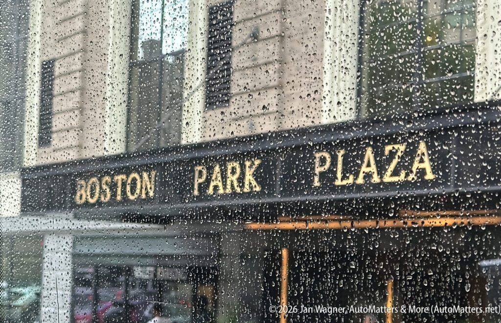 Boston Park Plaza hotel entrance sign seen through a rain-speckled window, with raindrops visible on the glass.
