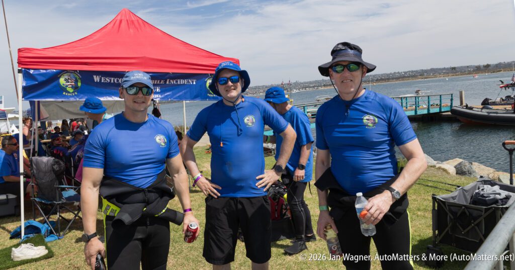 Three men in matching blue shirts and bucket hats stand by the water at a Westcoast Mobile Incident Rescue event.