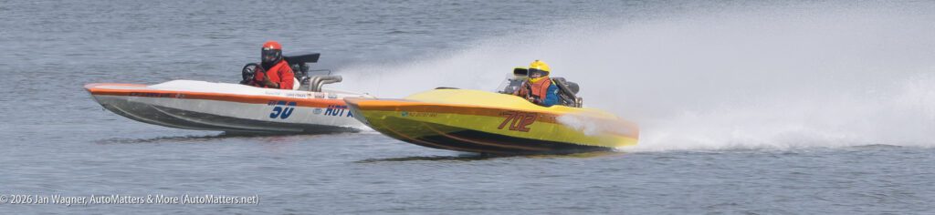 Two race boats speeding across the water, one white and one yellow.