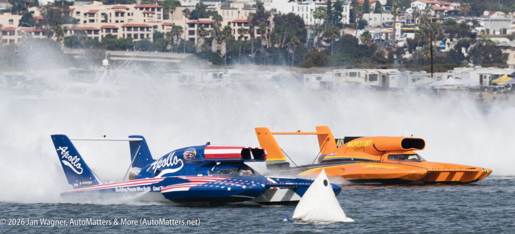 Two hydroplane race boats speeding across the water, kicking up large white sprays.
