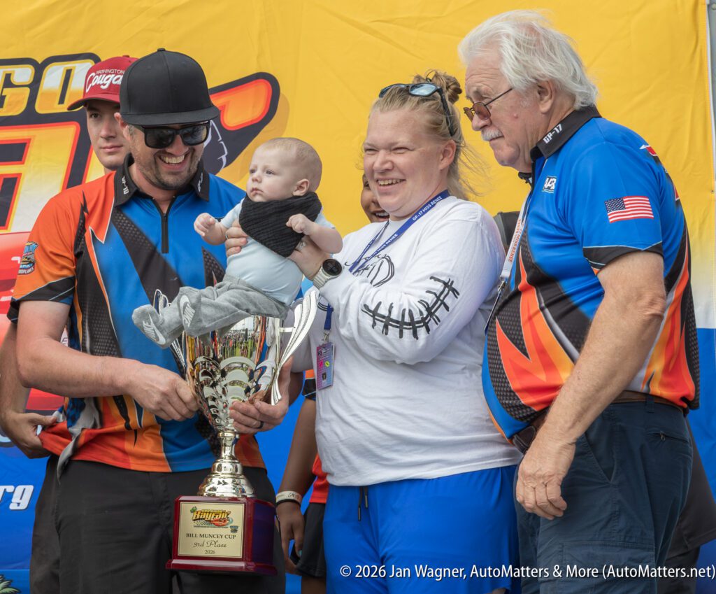 A team celebrating a third-place win, with a baby sitting inside a large silver Bill Muncey Cup trophy.