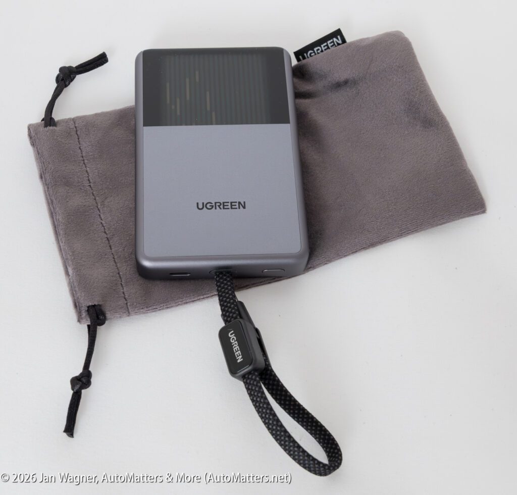 A UGREEN portable hard drive with a black wrist strap rests on a gray drawstring pouch.