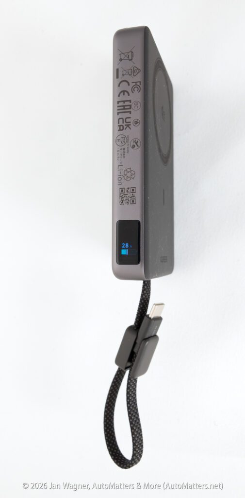 A black portable power bank with a small display showing 28% charge and an attached USB charging cable.