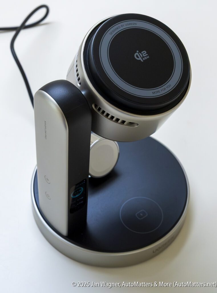 A wireless charging stand with a circular charging pad and adjustable arm, plugged in and placed on a white surface.