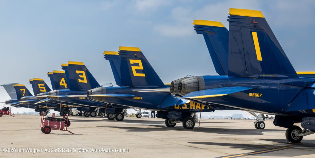 A line of U.S. Navy Blue Angels F/A-18 Hornet aircraft parked on a flight line, viewed from the rear, showing tail numbers 1 through 7.