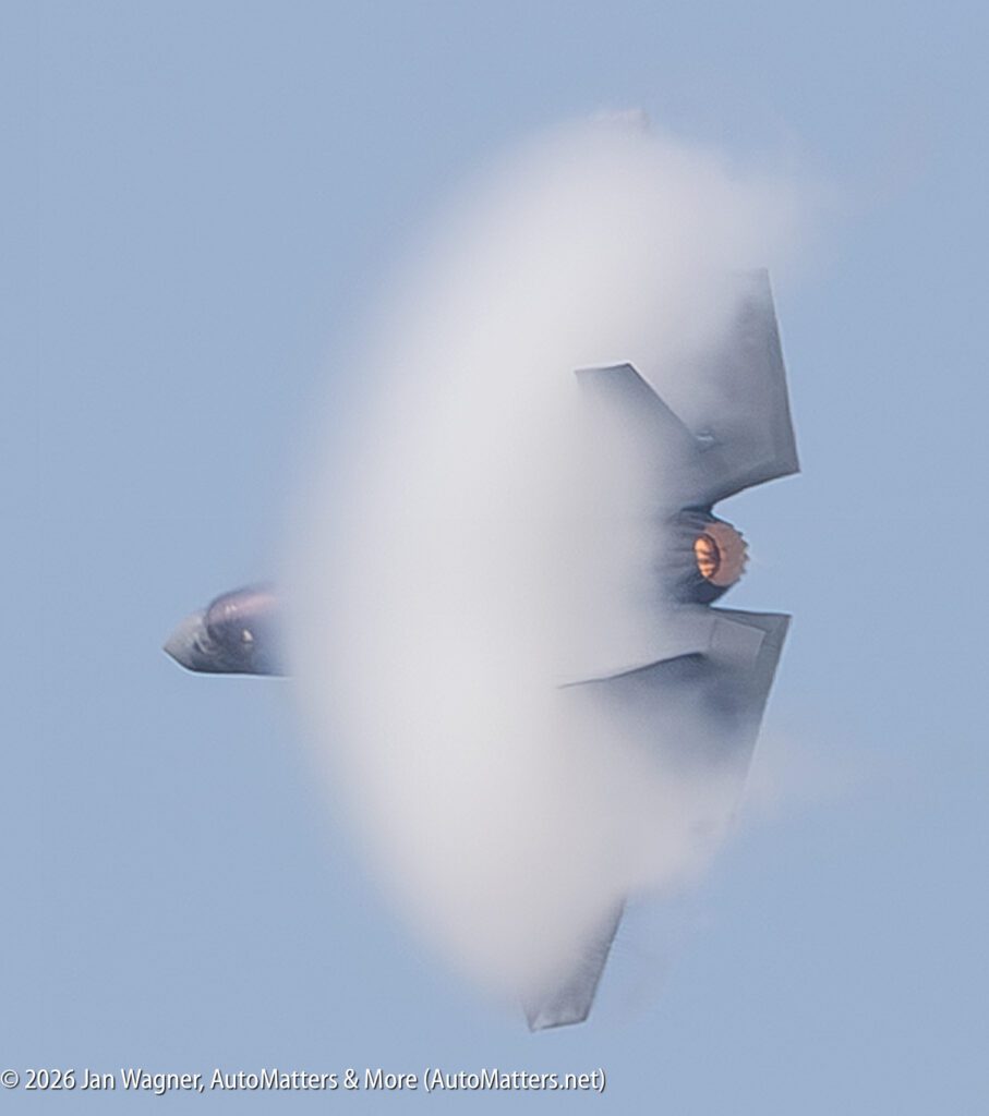 A fighter jet performing a high-speed maneuver, surrounded by a condensation cloud.