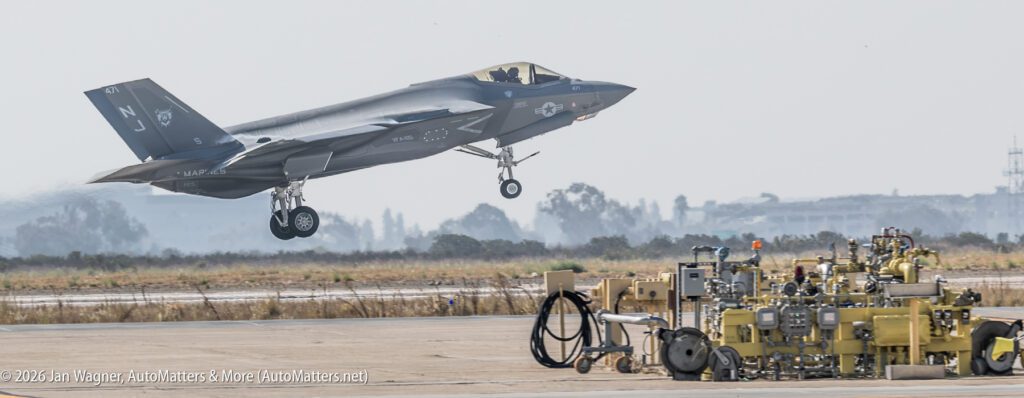 A US Marine Corps F-35 fighter jet taking off from a runway near ground equipment.