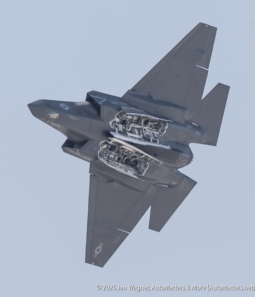 A US Navy F-35C Lightning II fighter jet in flight with its weapon bay doors open.