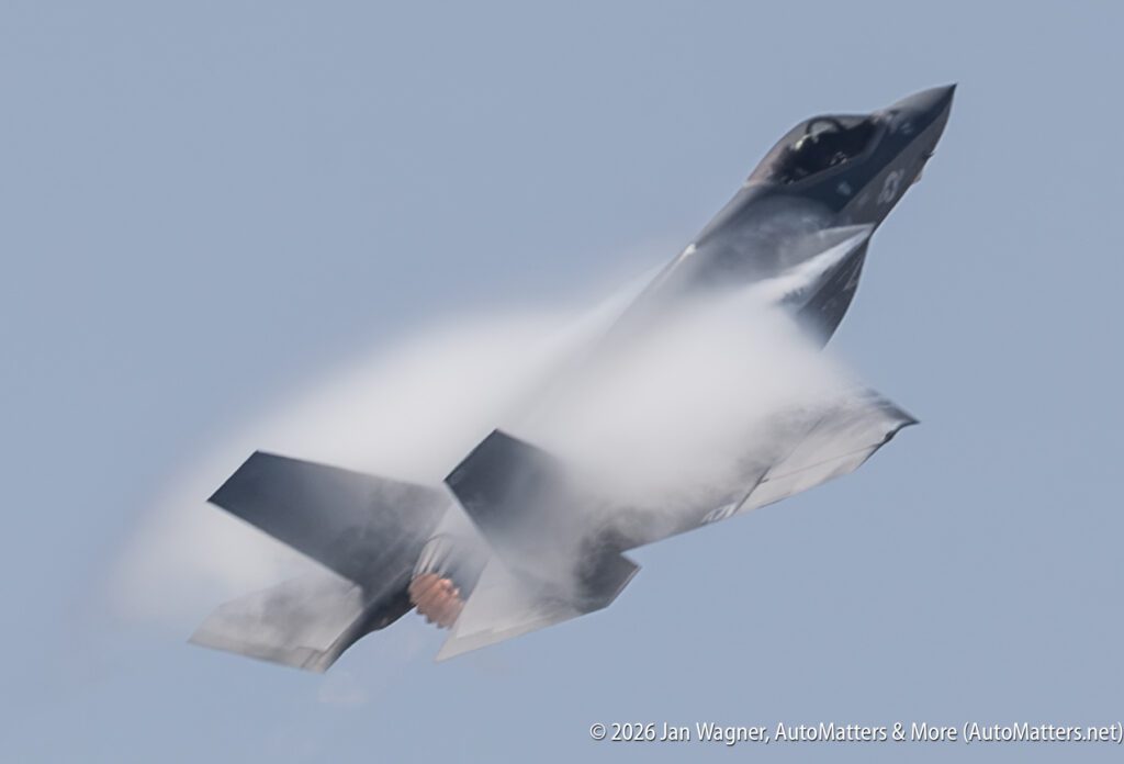 F-35 fighter jet in flight with vapor cloud over its wings.