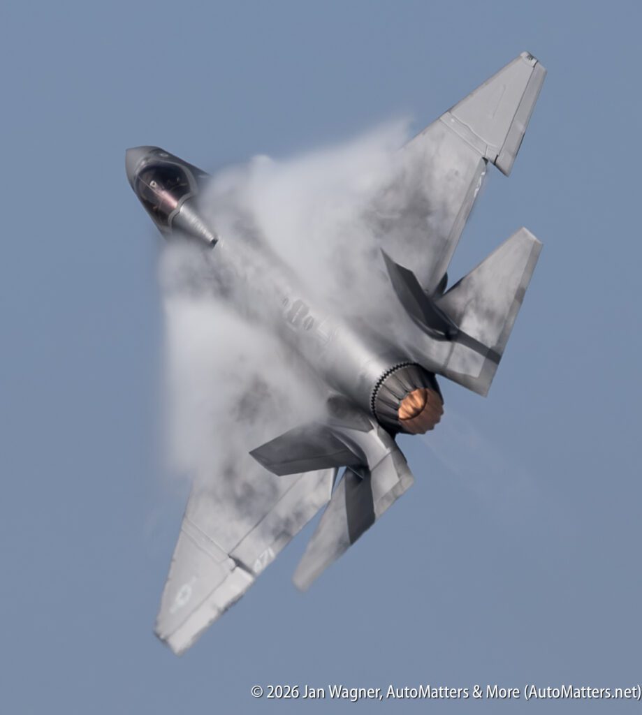 An F-35 fighter jet in a steep climb, generating a vapor cloud over its wings.