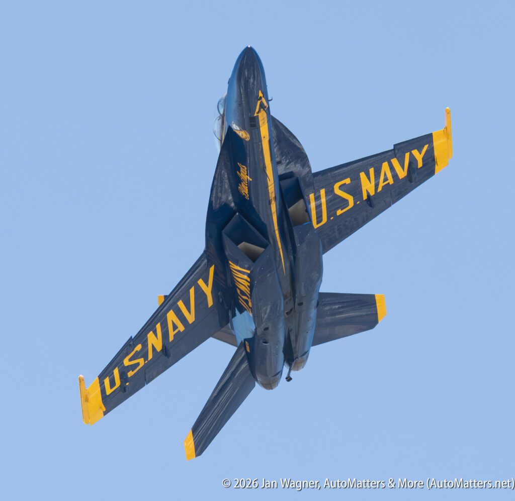 A U.S. Navy Blue Angels F/A-18 Hornet aircraft flying against a clear blue sky.