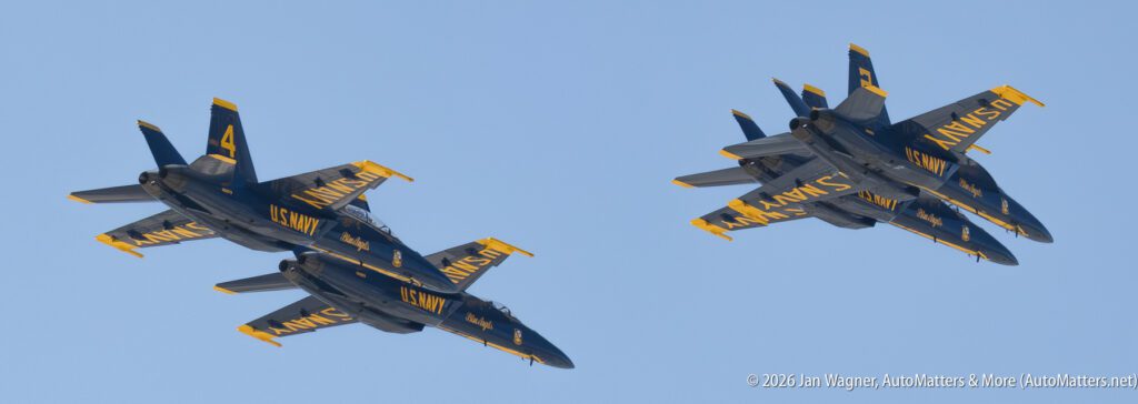 Two Blue Angels fighter jets flying in formation against a clear blue sky.