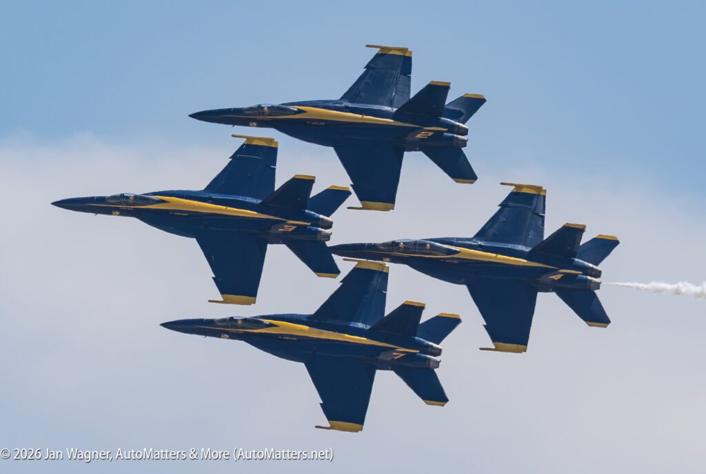 Four Blue Angels F/A-18 Hornet jets flying in a diamond formation against a blue sky.