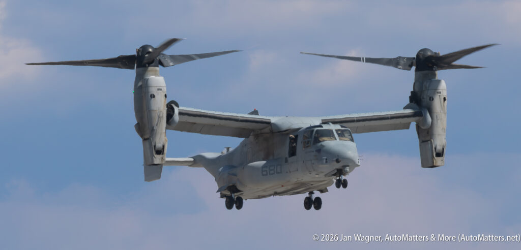 A V-22 Osprey tiltrotor aircraft in flight with its rotors tilted upward.