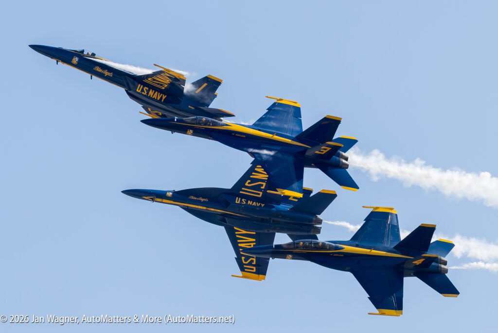 Four U.S. Navy Blue Angels F/A-18 Hornet aircraft flying in formation against a clear blue sky.