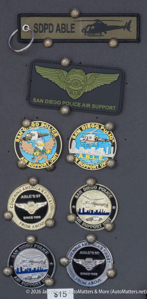 Collection of San Diego Police Air Support unit patches and challenge coins pinned to a display board.