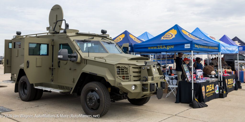 Olive green armored vehicle parked in front of DEA outreach tents.