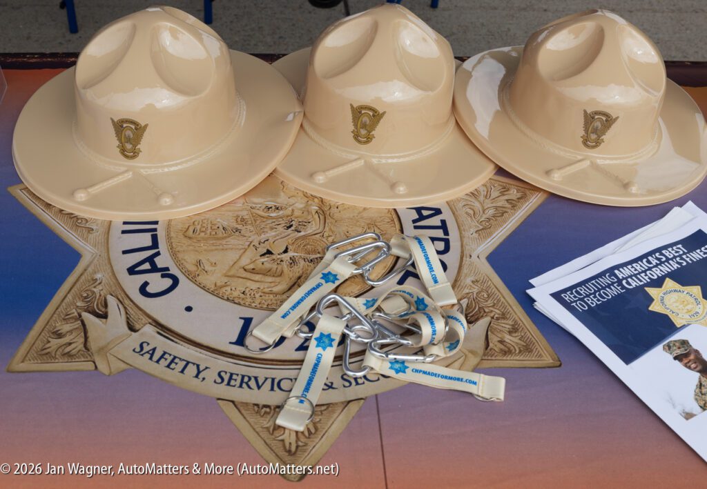 Three tan California Highway Patrol campaign hats arranged on a table over a CHP emblem, with lanyards and recruiting brochures.