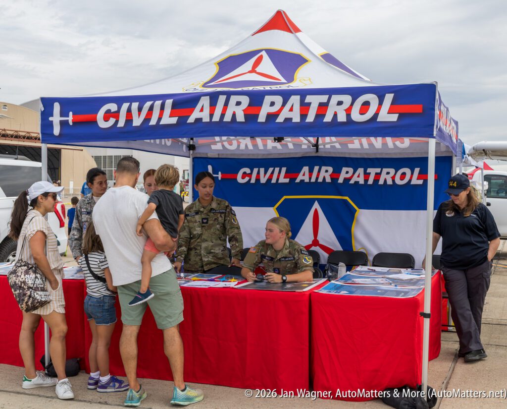 Civil Air Patrol recruitment booth at an outdoor event, with two uniformed members speaking to a family.