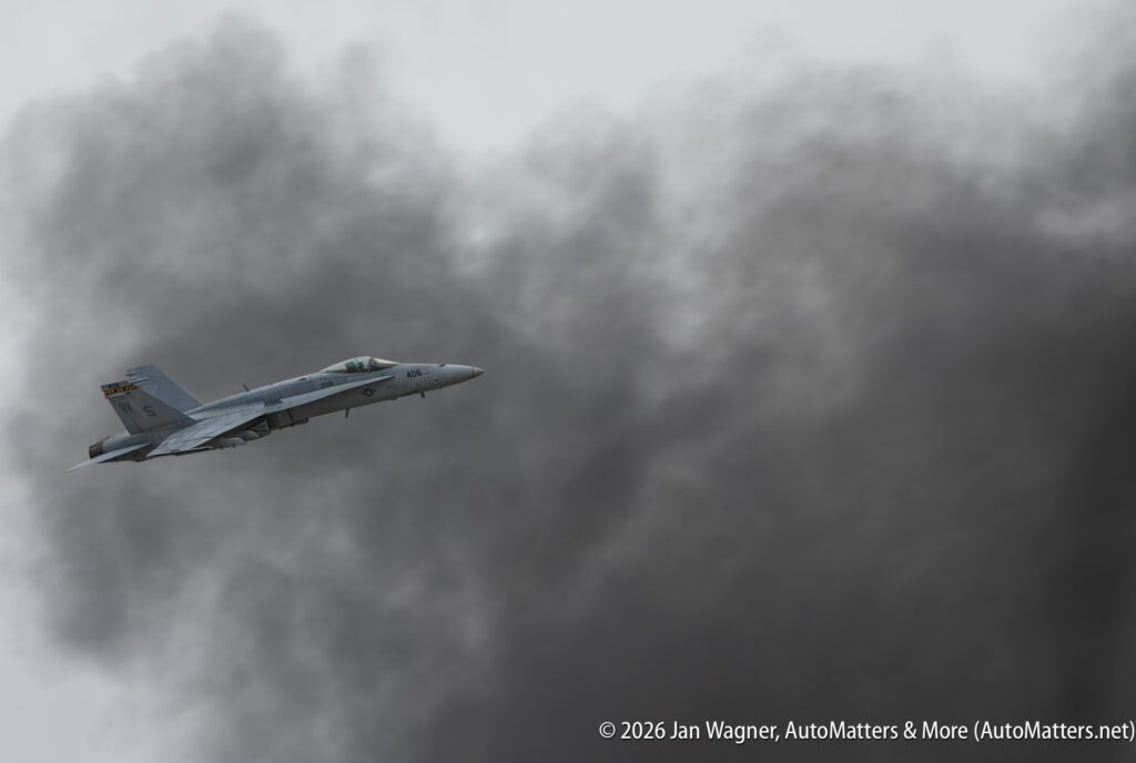 A fighter jet flying in front of a large plume of smoke.