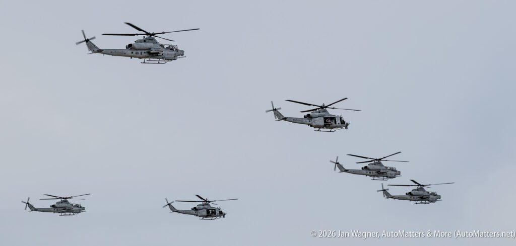 Five grey military helicopters flying in formation against an overcast sky.