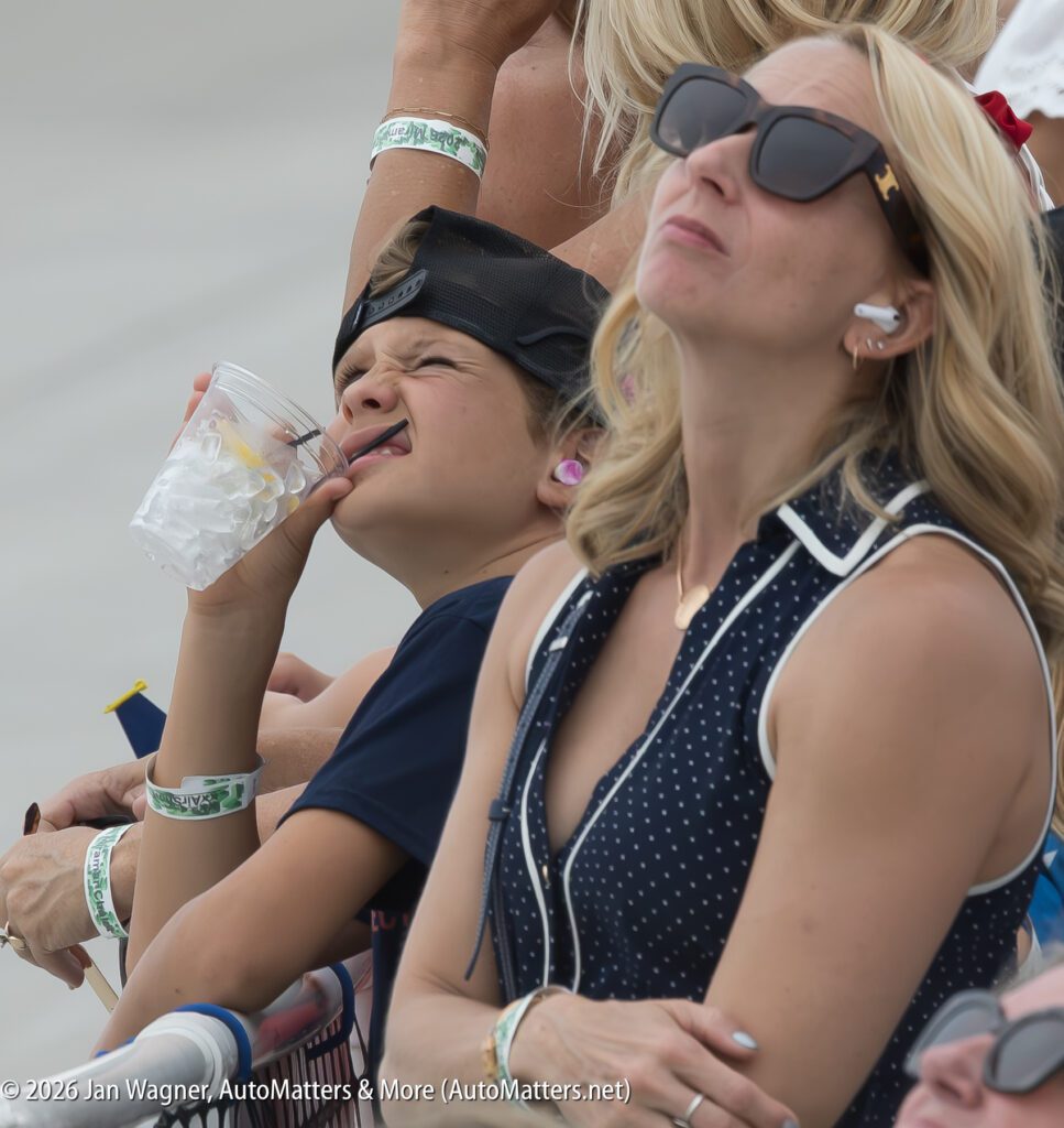 A young boy drinking from a plastic cup with a straw next to a woman wearing sunglasses.