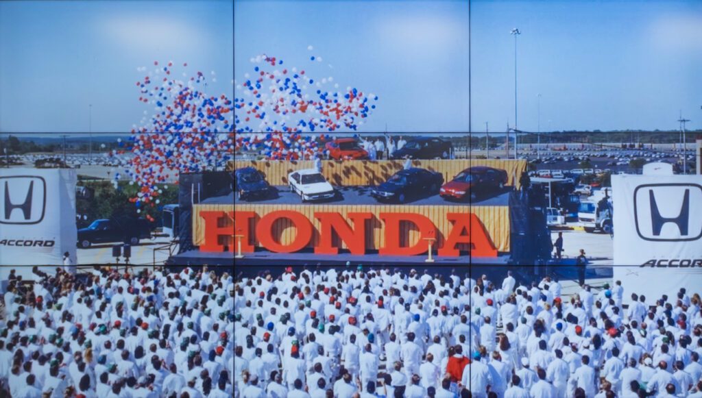 A large crowd watches a stage displaying four Honda Accord cars with a large “HONDA” sign and a red, white, and blue balloon release.