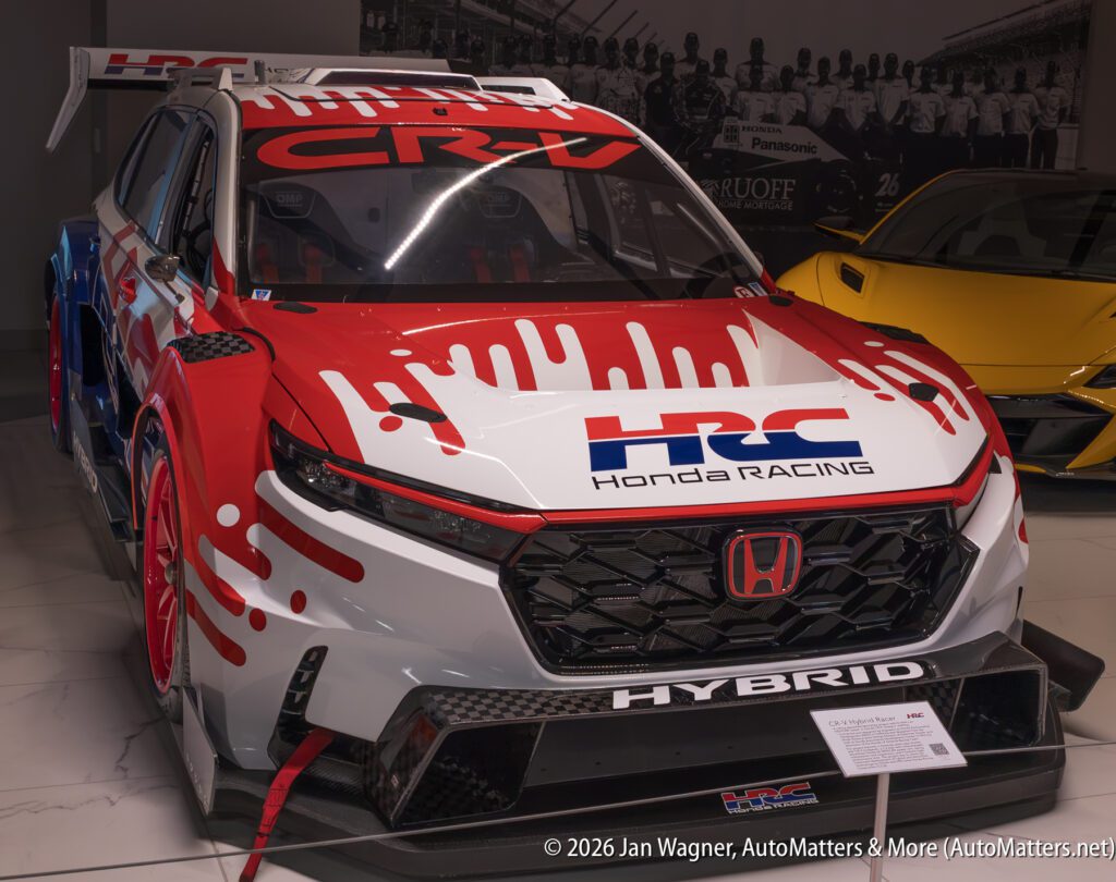 A Honda CR-V race car with red and white Honda Racing Corporation livery on display in a showroom.