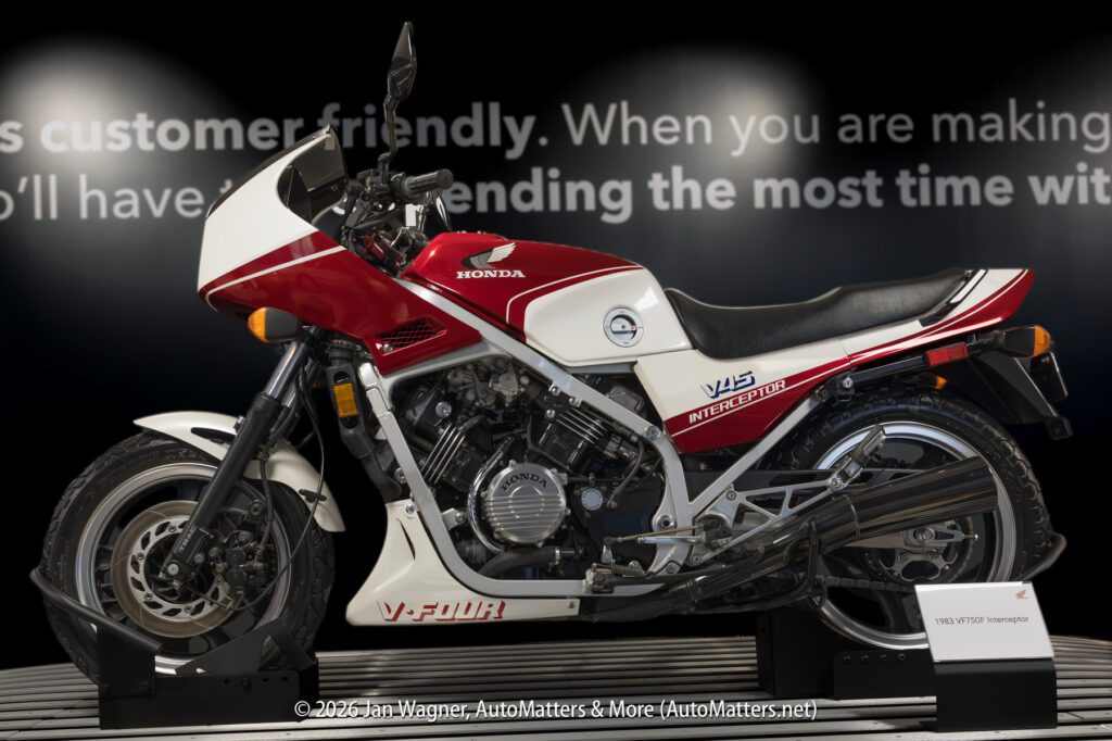 A 1983 Honda V45 Interceptor motorcycle in red and white on a display stand.