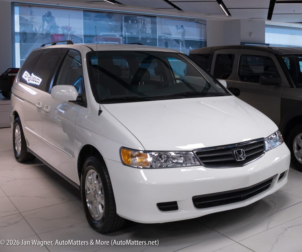 White Honda Odyssey minivan parked in a showroom.
