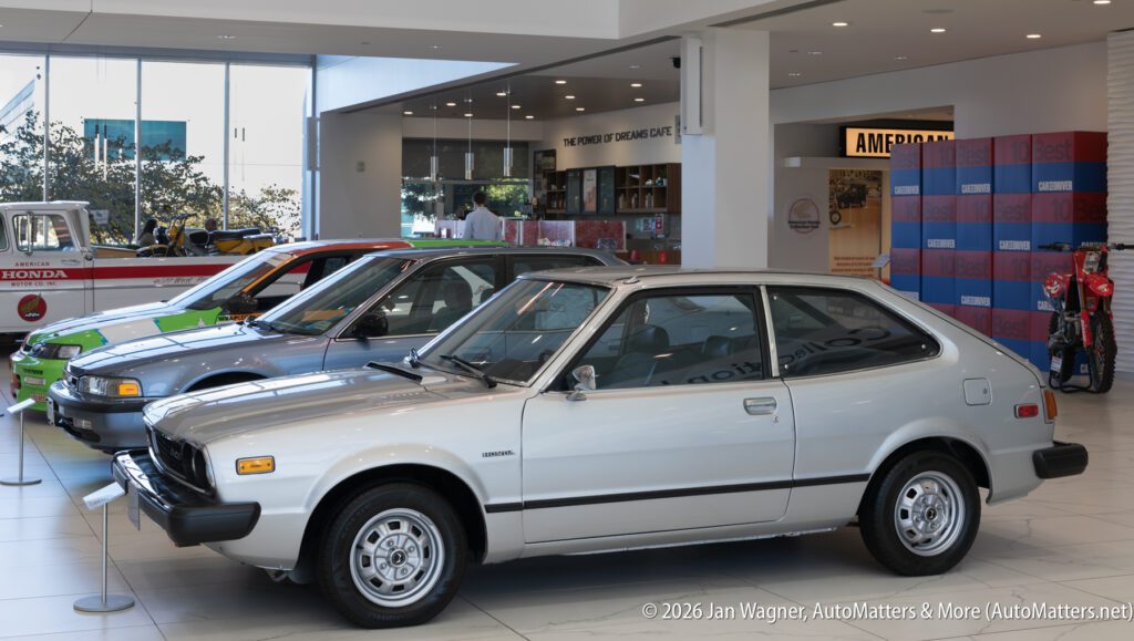 A line of vintage Honda vehicles displayed inside a dealership showroom.