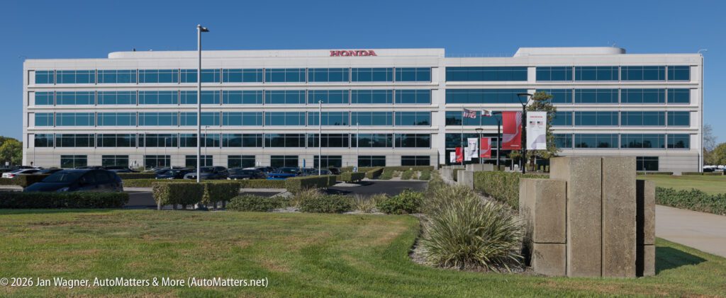 A large, multi-story office building with a Honda logo on the roof and a parking lot in front.